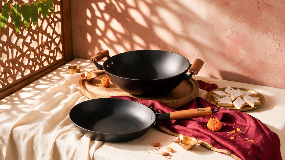 A cast iron kadhai and fry pan on a festive table with sweets and a diya
