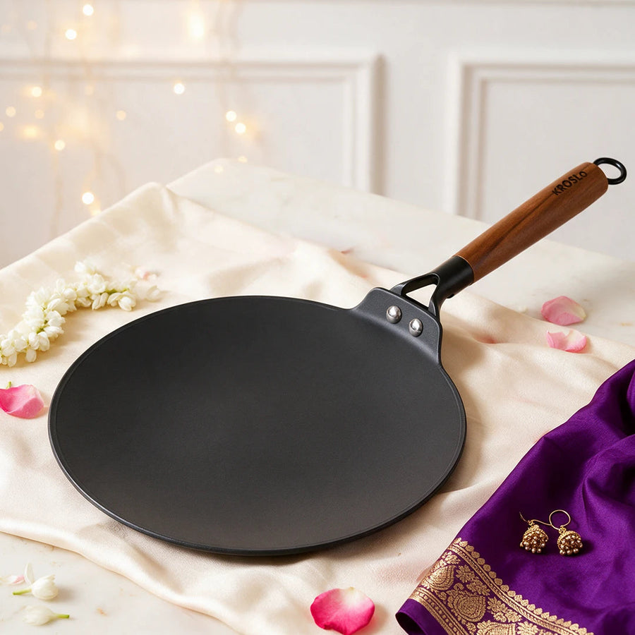 A cast iron roti tawa on cream silk with fairy lights and gold jewellery